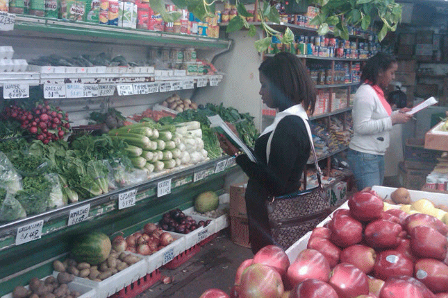 Two girls with clipboards in produce aisle of store